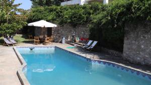 a swimming pool with chairs and a table and an umbrella at Traditional Luxury Villa ARMONIA in Aigio