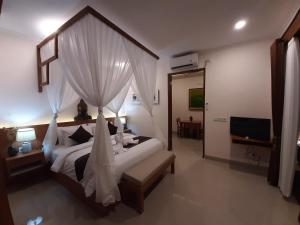 ein Schlafzimmer mit einem Bett mit Vorhängen und einem Fernseher in der Unterkunft The Satya Villa in Ubud