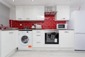 a kitchen with white cabinets and a washing machine at Calvin House Apartments in Leeds