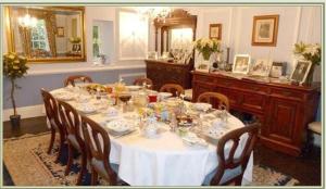 Queen Anne House في بورتلاند: طاولة طعام مع طاولة بيضاء من قماش وكراسي