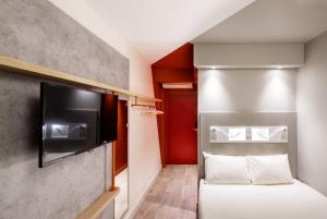 Cette petite chambre comprend un lit et une télévision à écran plat. dans l'établissement Ibis Budget Montpellier Nord Euromédecine, à Montpellier