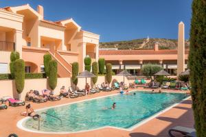 een groep mensen die rond een zwembad in een hotel zitten bij Luz casas- BayLuz apart,pool,beach, tennis, wifi,aircon in Luz