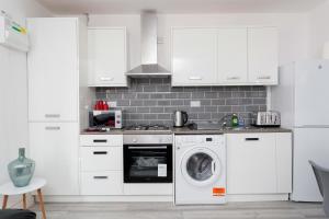 a kitchen with white cabinets and a washing machine at Calvin House Apartments in Leeds