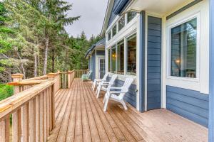 a deck with two white chairs on a blue house at Agate Beach Haven - 4 Bed 4 Bath Vacation home in Bandon in Bandon