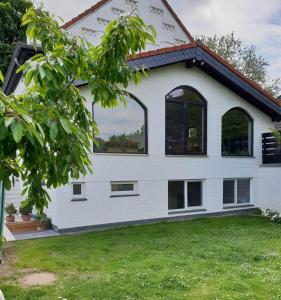 Cette maison blanche dispose de fenêtres et d'une cour. dans l'établissement Fischer Villa von 1875 - Kuscheliges Appartment im Grünen, à Meerbusch