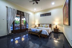 een slaapkamer met een kingsize bed en een patio bij Nyoman Sandi Guest House in Ubud