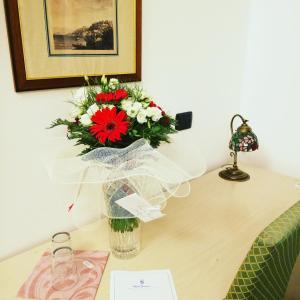 a vase filled with red and white flowers on a table at Hotel Fioroni in Bellagio