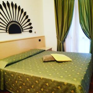 a bedroom with a green bed with a mirror on the wall at Hotel Fioroni in Bellagio