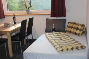 Cette chambre comprend une table et un lit avec une couverture. dans l'établissement Haus in der Kurve, à Kappl