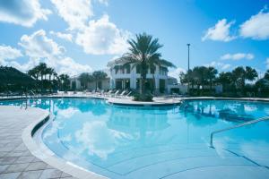 a large swimming pool with a palm tree and a building at Luxury Thownhouse with private pool in Kissimmee