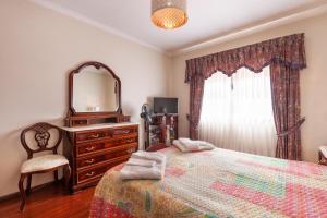 1 dormitorio con cama, tocador y espejo en Villa Madalena, en Coucieiro