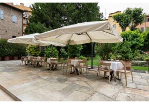 a group of tables and chairs under a large umbrella at Phi Hotel Canalgrande in Modena