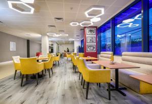 a dining room with yellow chairs and tables at Atrium Hotel Heathrow in Hillingdon