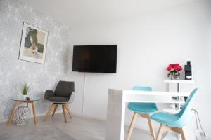 ein Wohnzimmer mit 2 Stühlen, einem Schreibtisch und einem TV in der Unterkunft Ferienwohnung Lörrach Alice in Lörrach