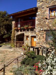 a stone house with a balcony and flowers in front of it at Hostal D'Éller in Éller