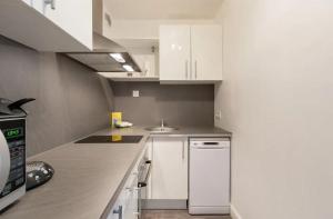 a small kitchen with white cabinets and a sink at Appartement Emeraude in Saint Malo