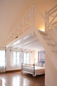 a white bedroom with a bed and a staircase at Tamarix Del Mar Suites in Kamari