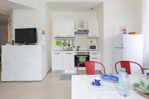 a kitchen with white cabinets and a table with red chairs at Casa Vermiglio al porto di Genova by Wonderful Italy in Genova