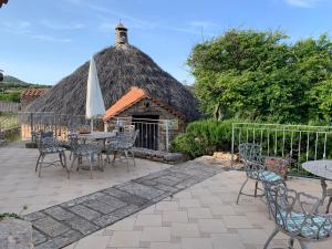 patio ze stołami i krzesłami oraz dachem krytym strzechą w obiekcie Agriturismo Sa Perda Marcada w mieście Arbus