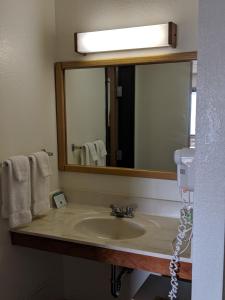 a bathroom with a sink and a large mirror at Boarders Inn and Suites by Cobblestone Hotels - Ripon in Ripon
