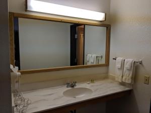 un bagno con un lavandino e un grande specchio di Boarders Inn and Suites by Cobblestone Hotels - Ripon a Ripon