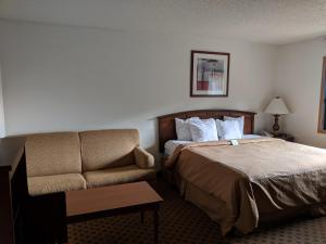 ein Hotelzimmer mit einem Bett und einem Sofa in der Unterkunft Boarders Inn and Suites by Cobblestone Hotels - Ripon in Ripon