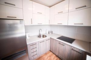 La cuisine est équipée de placards blancs, d'un évier et d'un réfrigérateur. dans l'établissement Teatra32 Sunshine Home, à Daugavpils