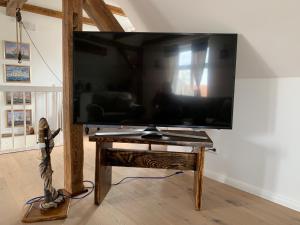 una grande TV a schermo piatto su un tavolo di legno di Haus Vicus a Greifswald