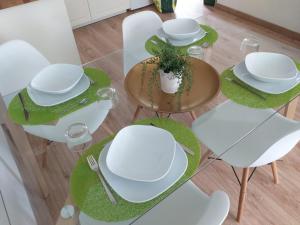 einen Tisch und Stühle mit weißen Platten und einer Pflanze in der Unterkunft Casita verde vista mar in Parque Holandes