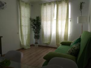 ein Wohnzimmer mit einem grünen Sofa und Fenstern in der Unterkunft Casita verde vista mar in Parque Holandes