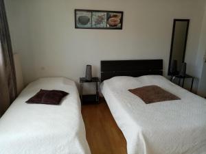 two beds in a room with white sheets and brown pillows at Hôtel de la poste in Saint-Valery-en-Caux