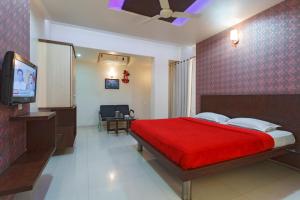 戈爾哈布爾的住宿－Hotel Vrindavan Deluxe Kolhapur，一间卧室配有红色的床和电视