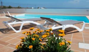 a pool with two chairs and a table and flowers at Apartamento Casa Belen in Conil