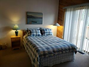 a bedroom with a bed with a blue and white blanket at Invermere Luxury 4 Bedroom Mountain Lake View Home - Sleeps 8, 2 decks, Huge Yard, Walk to Town -Beach, Tennis, Golf at 12 Courses - Hot Springs Close By!! in Invermere
