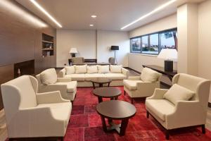 a living room with white couches and tables and chairs at Hotel Parentium Plava Laguna in Poreč