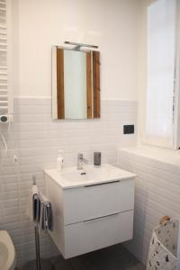 W białej łazience znajduje się umywalka i lustro. w obiekcie Rho-Fiera - Appartamento in antica cascina w mieście Pero