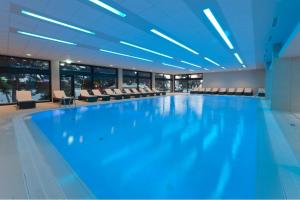 a large swimming pool in a building with chairs at Hotel Parentium Plava Laguna in Poreč