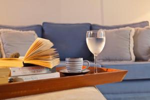 a coffee table with a glass of wine and books at Tamarix Del Mar Suites in Kamari