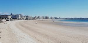 Blick auf einen Strand mit Gebäuden im Hintergrund in der Unterkunft Cassiopée II Appt Classé 3 étoiles 2 chambres terrasse garage in Les Sables-dʼOlonne