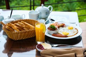 a breakfast table with a plate of breakfast foods and orange juice at Aloft Grand Hotel Ella in Ella