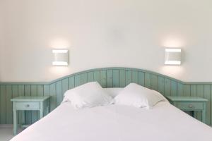 1 cama blanca con 2 almohadas y 2 mesas en Hotel Restaurant Juanito Platja en Sant Carles de la Ràpita