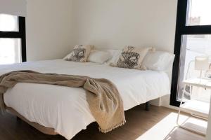 a bedroom with a white bed with pillows on it at GoToSeville GERONA SUITES in Seville