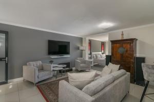 a living room with a couch and chairs and a tv at Blue Moon Apartments in Knysna
