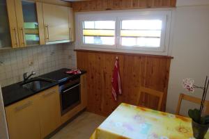 een keuken met houten kasten, een wastafel en een raam bij Haus Bergkristall in Herbriggen