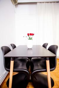 a black dining table with black chairs and a vase of flowers at Thessaloniki Center Apartment On The Sea in Thessaloniki