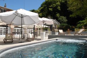 a swimming pool with umbrellas and chairs and a table at Domaine de Joinville in Eu