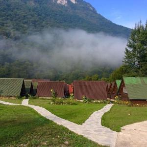 a group of houses with a mountain in the background at Lux bungalow in Foča