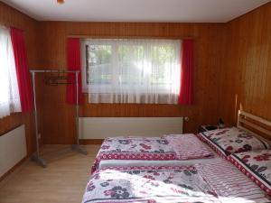 twee bedden in een slaapkamer met rode gordijnen en een raam bij Wohnung Wohlensee in Hinterkappelen