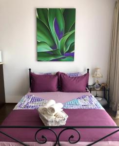 a bedroom with a purple bed with a painting on the wall at Студио Панорама Сънрайз Бяла - кът за отдих и морска почивка in Byala