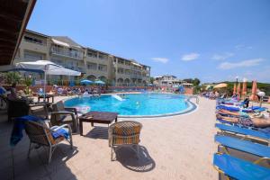 a swimming pool with chairs and people sitting around it at Socrates Hotel in Sidari